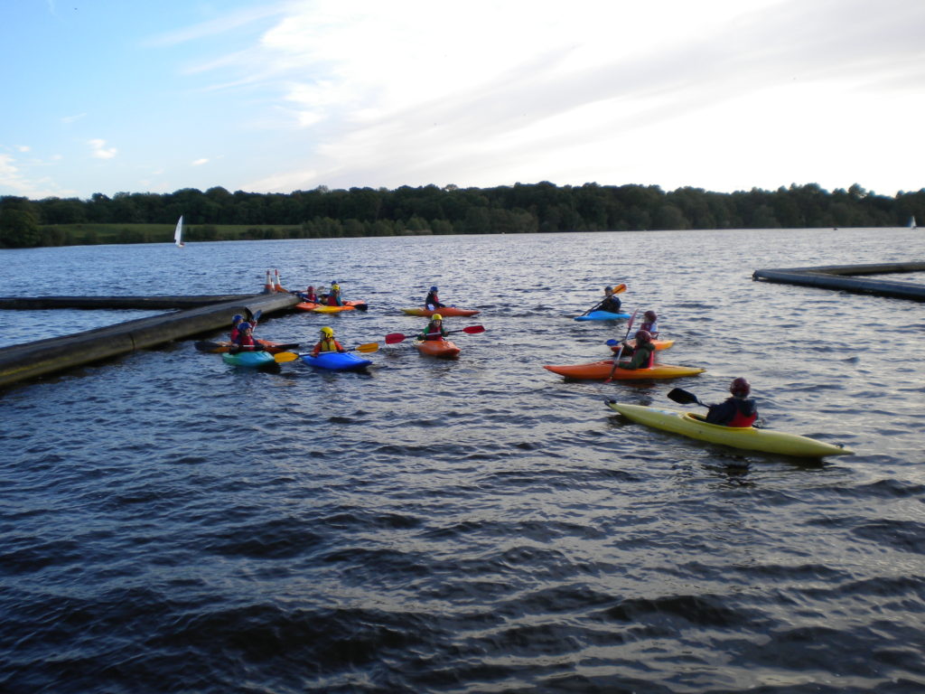 scouts kayaking between two piers. The boats are colourful.